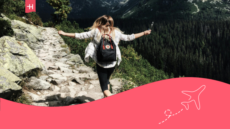 Alt text for featured image: Traveler with a backpack hiking in a skipping pace along a rocky mountain trail, surrounded by deep valleys covered in dense green forests.