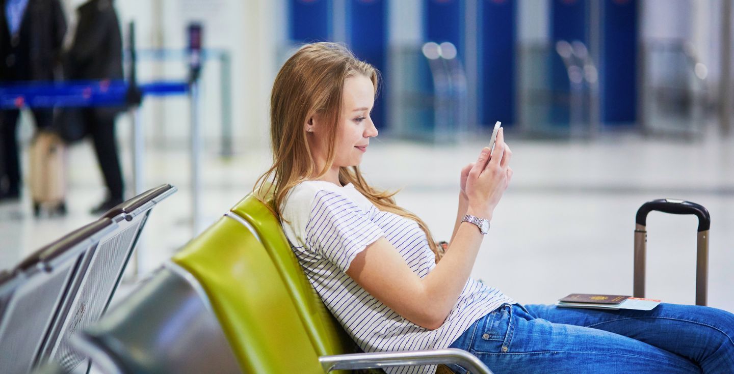 woman using phone with an esim at an airport