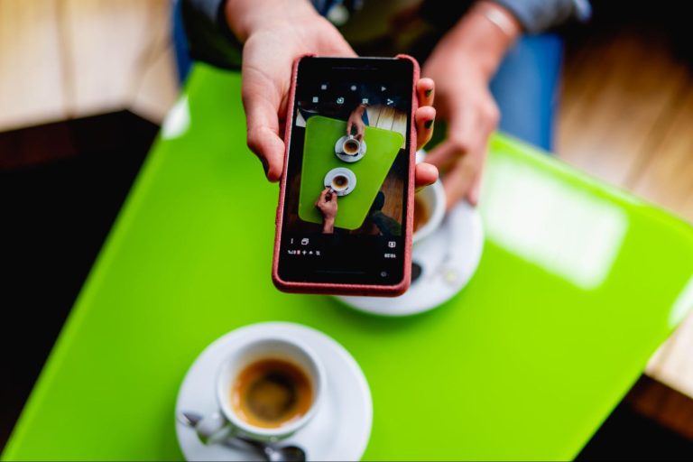 A person is holding a smartphone above a green table. 