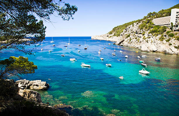 Aerial photos of sailboats and yachts sailing in the blue waters near the The Resort of Portinatx in Ibiza.