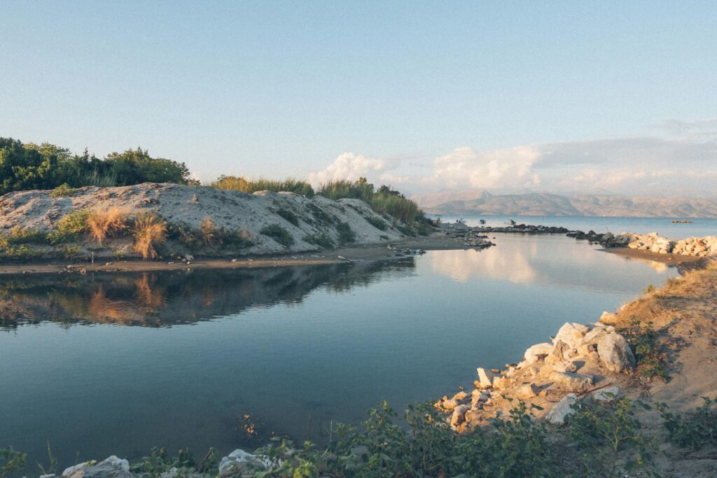 Serene landscapes of Corfu, where calm waters meet rugged shores and distant mountains.