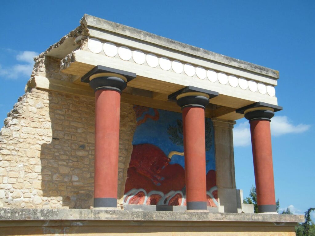 The ruins of Knossos Palace in Crete, showcasing the vibrant red columns and ancient frescoes of the Minoan civilization.