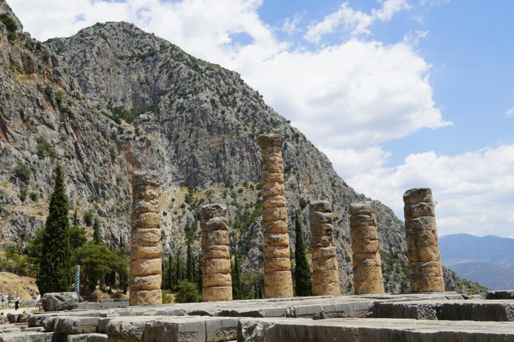 The ruins of the Temple of Apollo in Delphi, set against the dramatic mountain landscape of Greece.