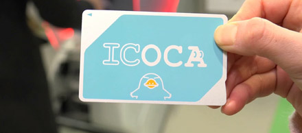 A photo of a person holding the ICOCA card. Which is a white and light blue card with a blue platypus (Ico) doodle. 