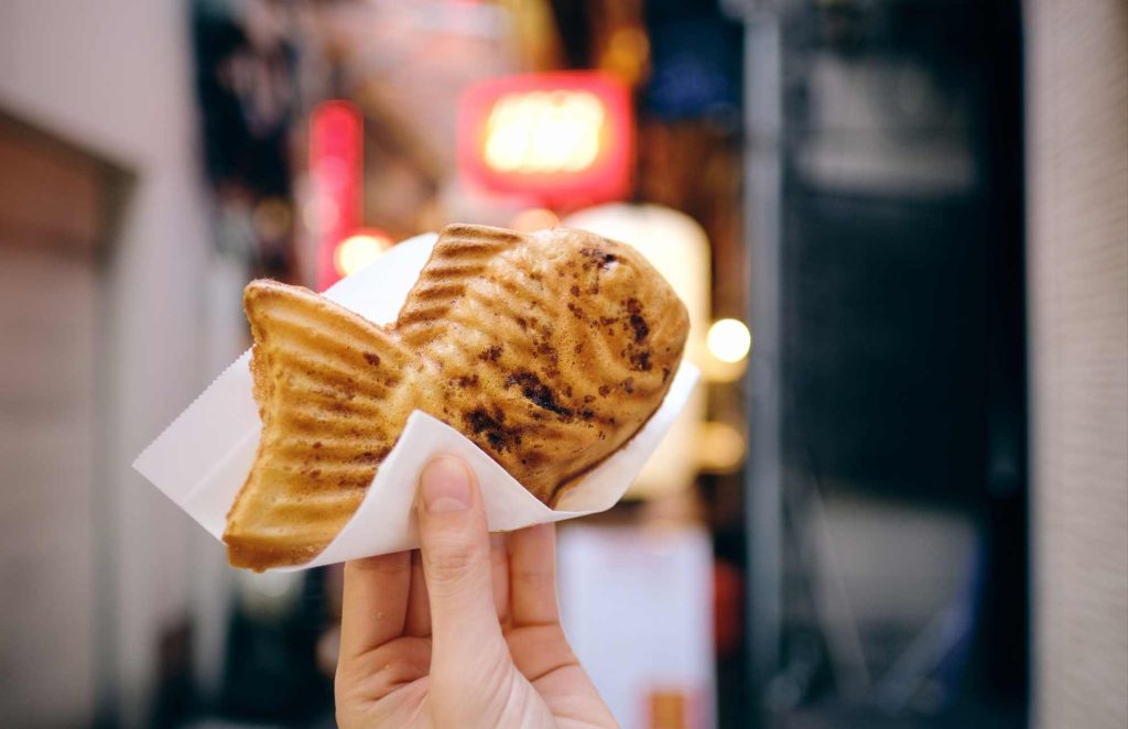 taiyaki, fish-shaped sweet cakes being held in a napkin 