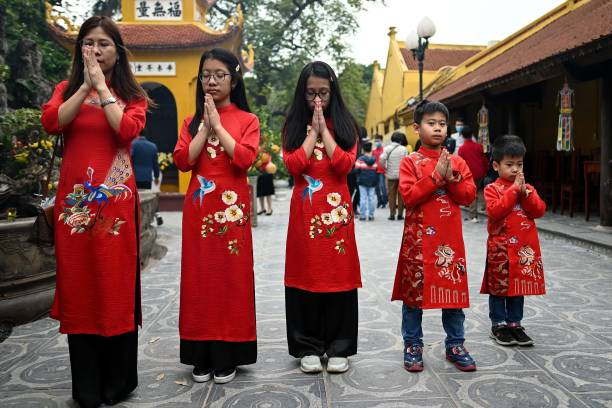 A Vietnamese family of five wearing the traditional Ao Dai dress and praying in a pagodo during Tet festival.