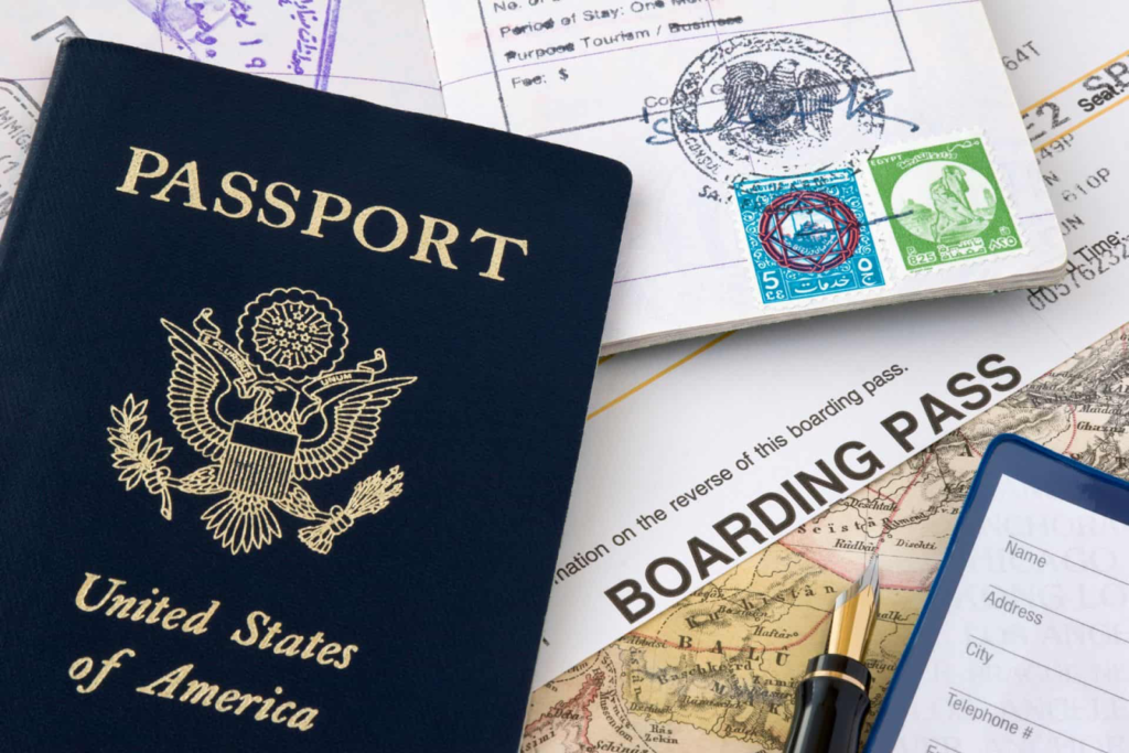 Some travel documents like passport, visa papers, and boarding pass scattered on a table.