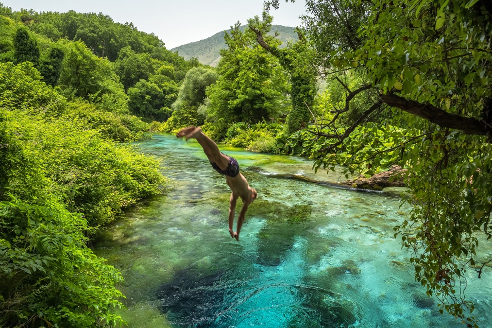 A person diving into the Blue Eye Springs in Albania