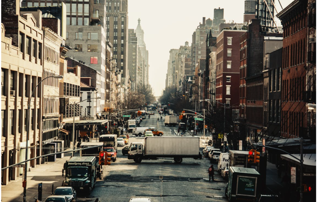 A bustling street scene in Chelsea, with trucks, vehicles, and buildings lining the avenue. Source: Pexels