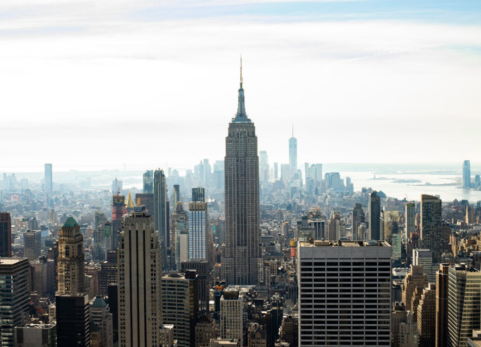 Aerial view of the Empire State Building surrounded by other high-rise buildings and a hazy sky Source: Pexels