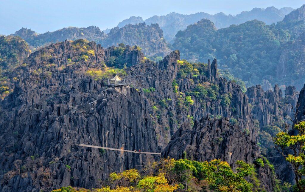 Two people crossing the spider net bridge at the Rock Viewpoint in Laos