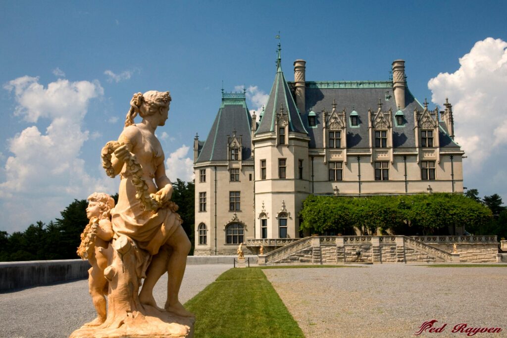 The Biltmore Estate with a statue in the foreground and gardens leading up to the historic house.