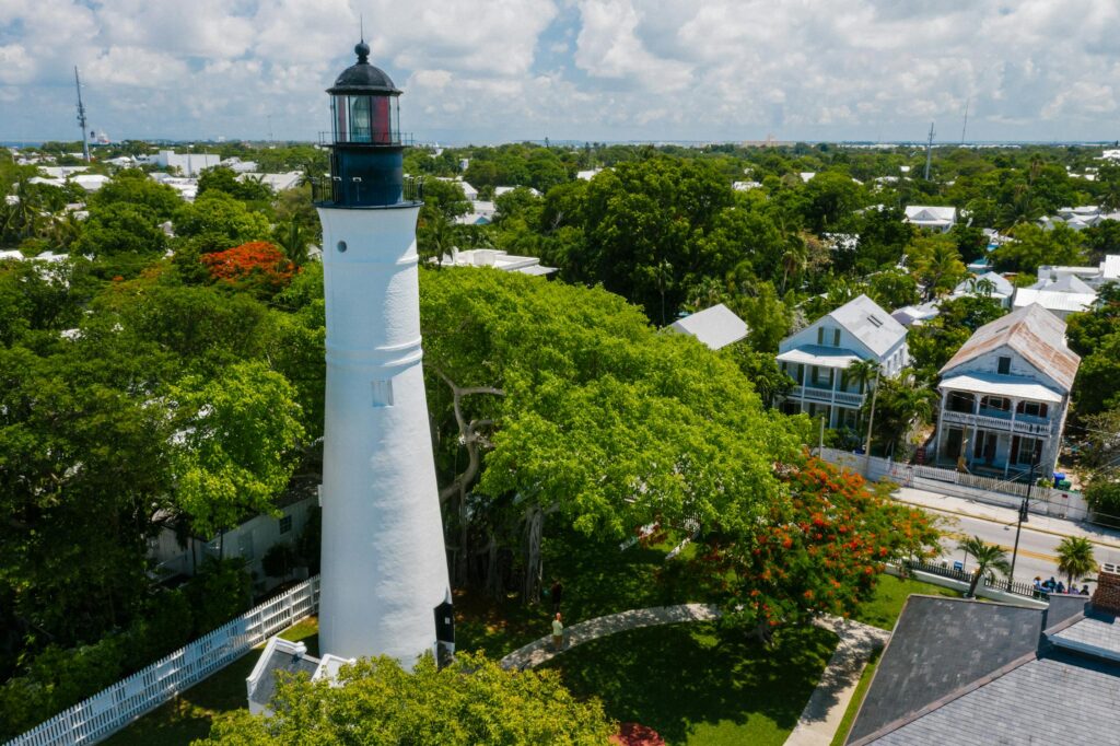 Aerial view of the the Key West Lighthouse surrounded by white villas and lush vegetation.