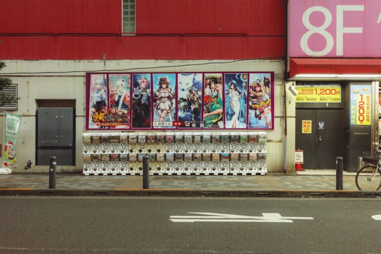 A street in Japan with multiple anime posters on the wall.