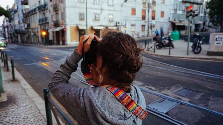 A young traveler taking photos with a digital camera in the streets of Portugal.
