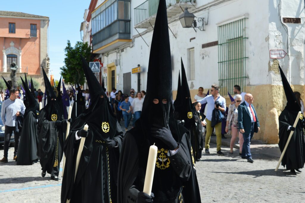 Penitents from a confraternity participate in a traditional Semana Santa procession in Seville, wearing black capirote as part of Holy Week observances before Easter