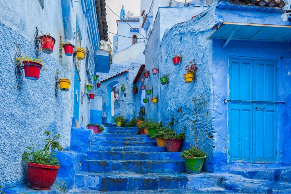 The city of Chefchaouen, or “Blue Pearl” with colorful potted plants strewn up stairs and hanging from outer building walls