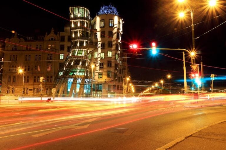 Illuminated Dancing House in Prague at night with blurred car lights.