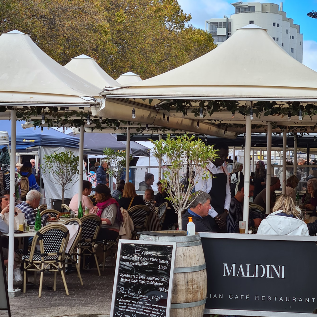 A cafe on the sidewalk in Salamanca Place during rush hour.