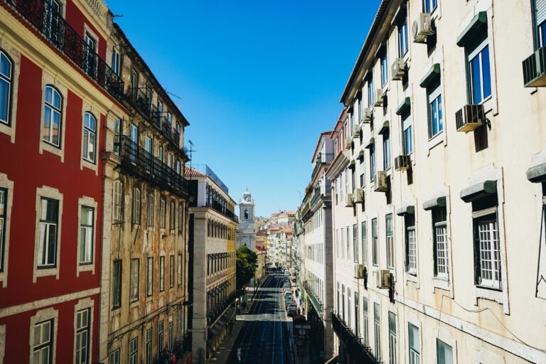 The streets of Portugal with colorful buildings providing shade on a sunny day