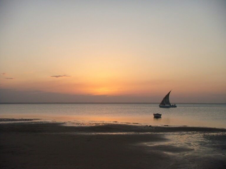 A sailboat glides on the water with a majestic sunset in the background in the Bazaruto Archipelago