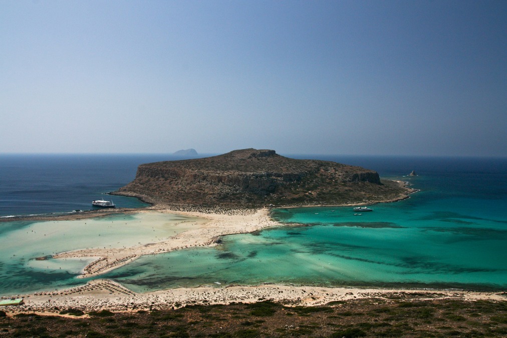 A small island sits in the middle of turquoise waters