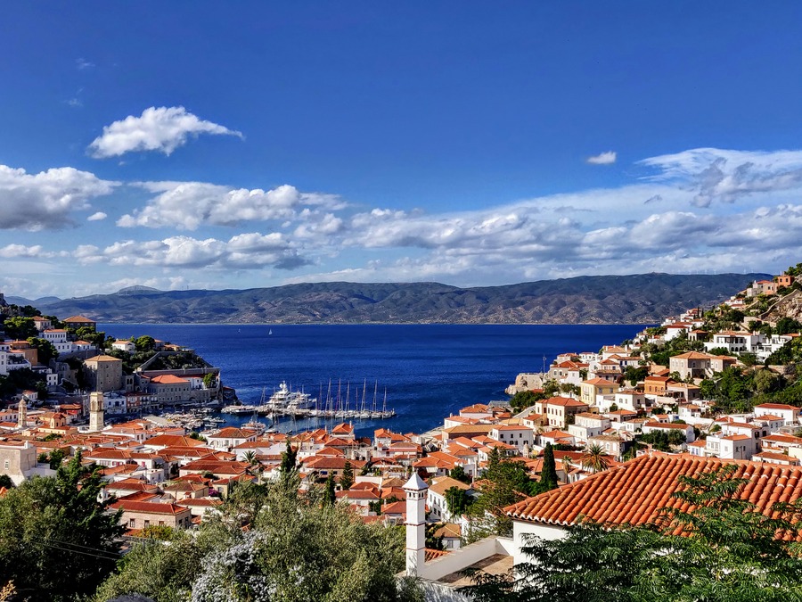 Red Mediterranean-roofed houses sit before the vast blue 