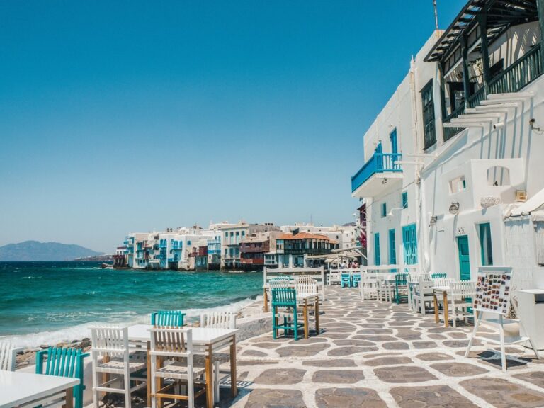 White and blue architecture sits against blue waters in Mykonos, Greece