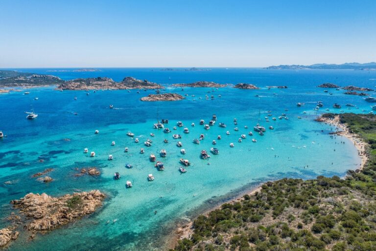 Numerous boats, yachts, and private cruises are scattered on blue waters in Sardinia, Italy