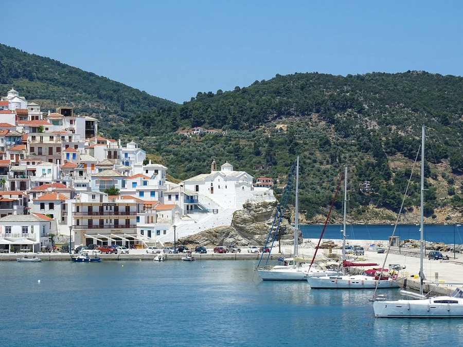 White boats are parked in a harbor, surrounded by quaint Mediterranean-style houses 