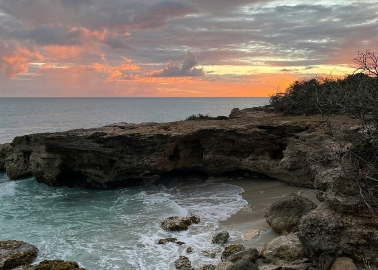 Eroded rock structures and secluded shores against an orange sunset in St. Croix Island in The U.S. Virgin Islands