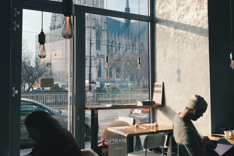 A cafe in Vienna, with people inside and beautiful architecture outside the window.
