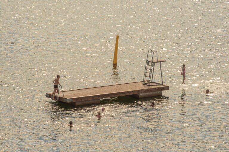 Children jumping off a floating pontoon in the middle of the sea in Norway during summer.