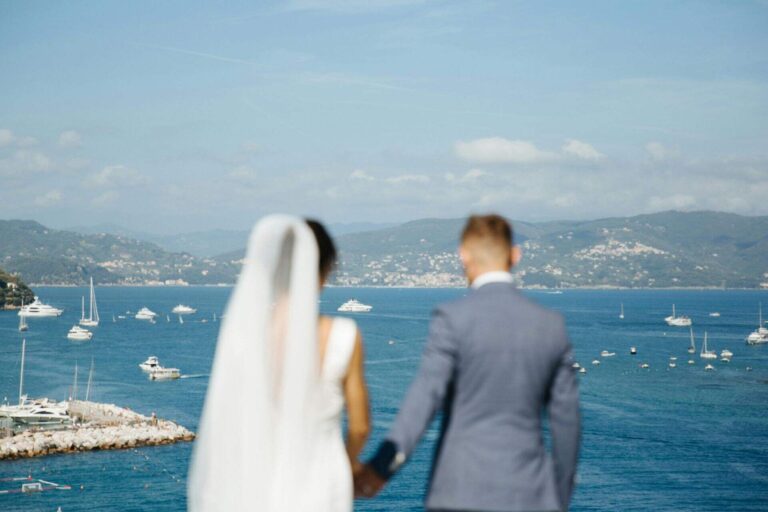 A newlywed couple standing over the seaside in Italy