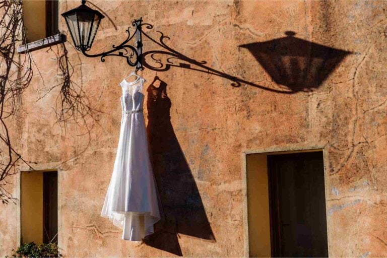 A wedding dress hanging outside by a wall in Italy