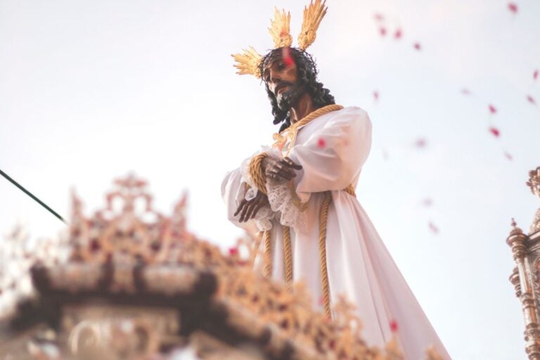 Day shot of Semana Santa parade. Statue of Jesus with a crown atop a wooden float.