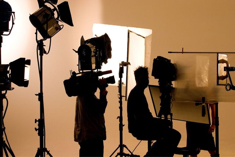Shot of three people's shadows working with various pieces of camera equipment.