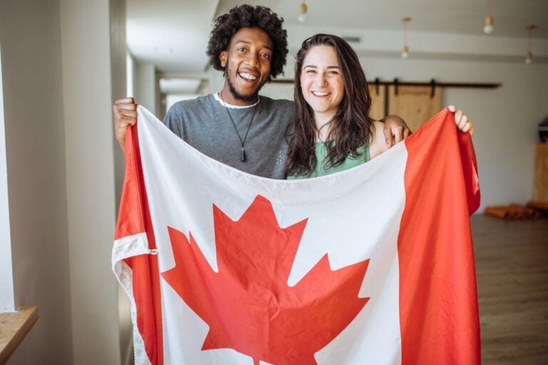 A man and a woman holding up a Canadian flag.