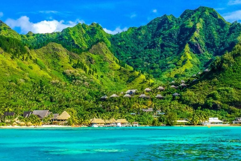 The mountains of Tahiti, French Polynesia dotted with houses, beach and shoreline.