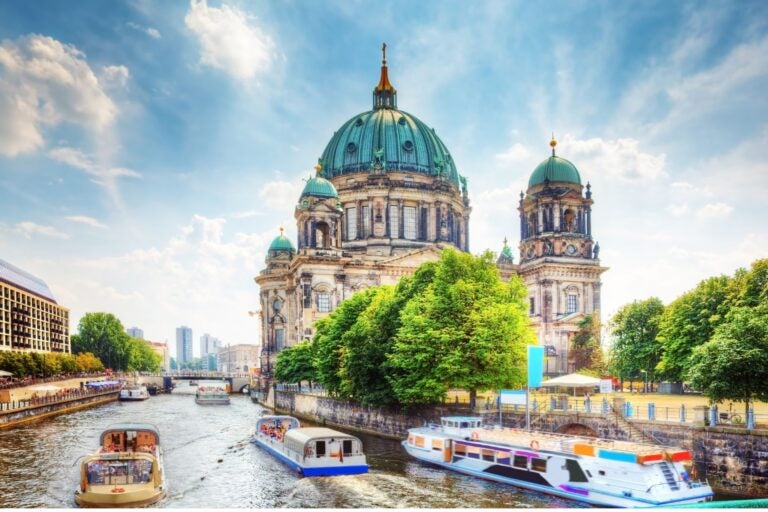 Sunny day time shot of Berliner Dom, or Berlin Cathedra, with boats traveling up and down the Danube river.