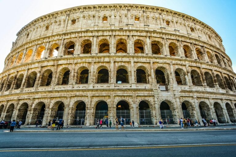 Rome Colosseum seen from across the street with tourists walking by