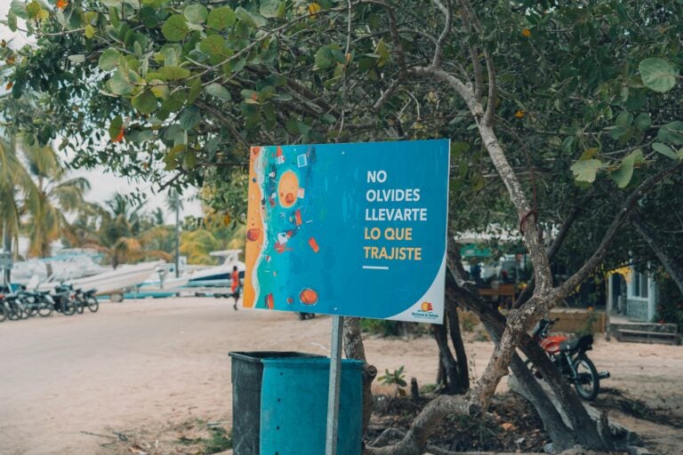 A sign on the beach asking people not to forget to take their trash with them when they leave. The sign is in Spanish.