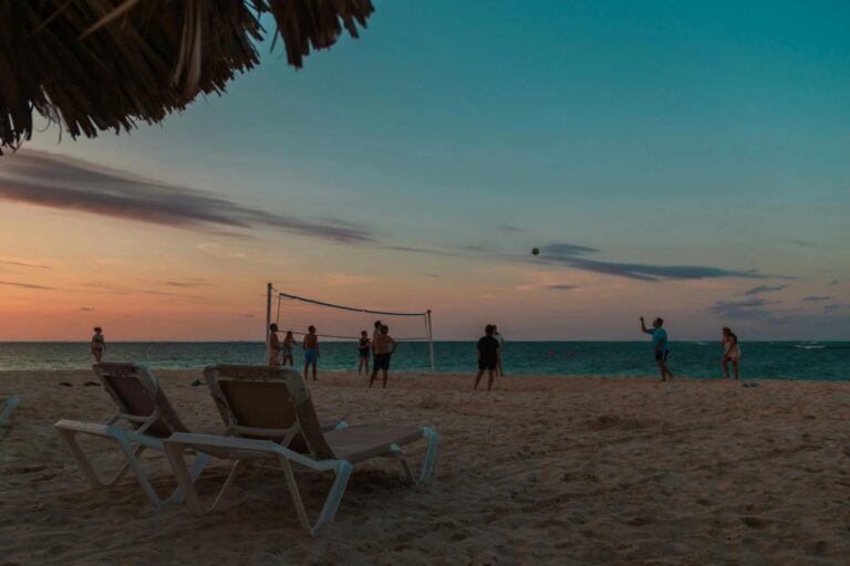 Sun loungers in front of people playing volleyball at dusk in Punta Cana.