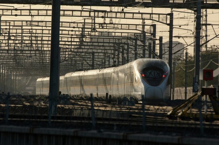 the silver-colored aerodynamic bullet trains of Japan approachng on train tracks 