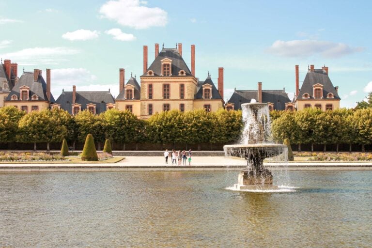 Château de Fontainebleau, outdoor fountain, and people walking around it
