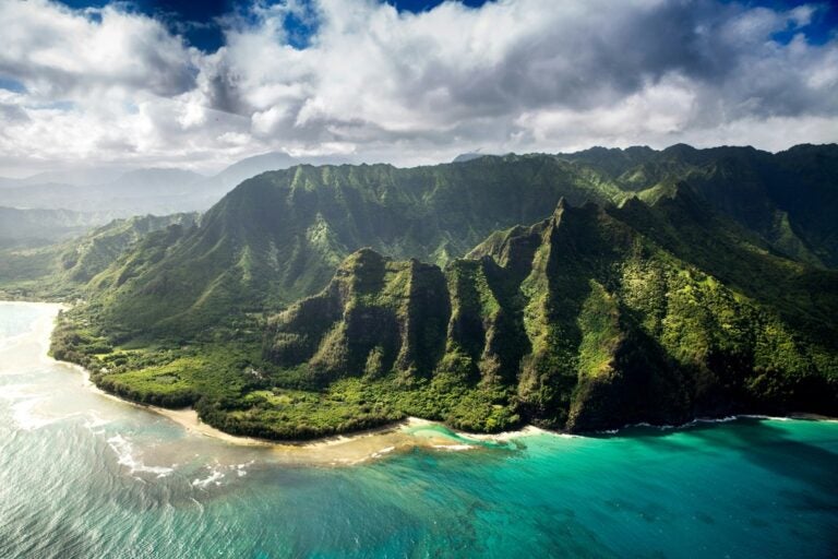Green mountains and teal waters on Kauai island's coastline