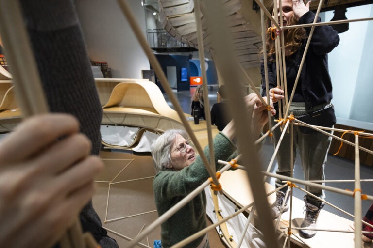 a woman in an interactive exhibit in the new york hall of science tying sticks together