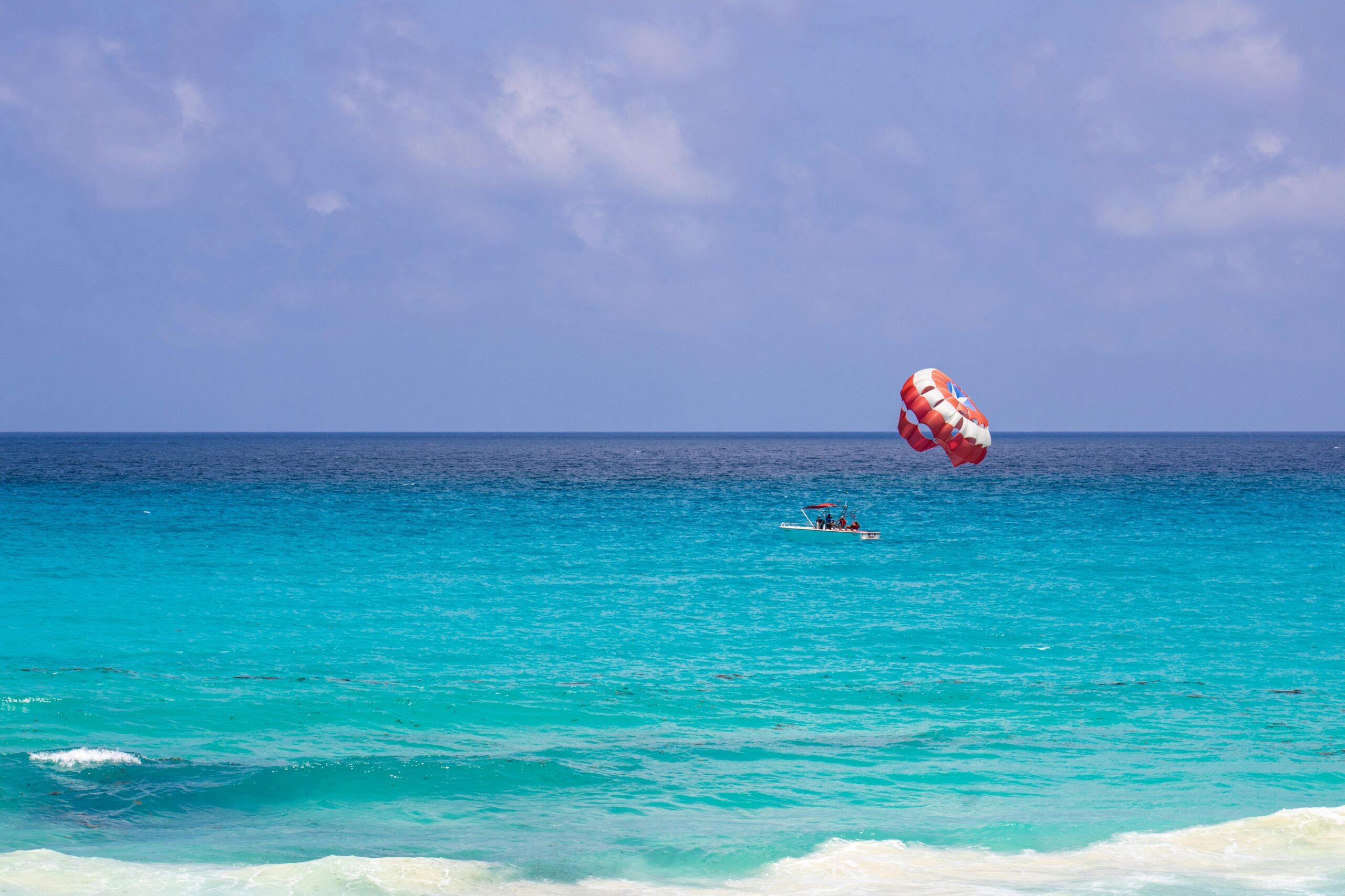 A boat preparing to send paragliders into the air above the back of the boat. 