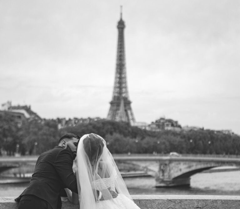 a couple in a tux and wedding gown in front of the Eiffel tower 