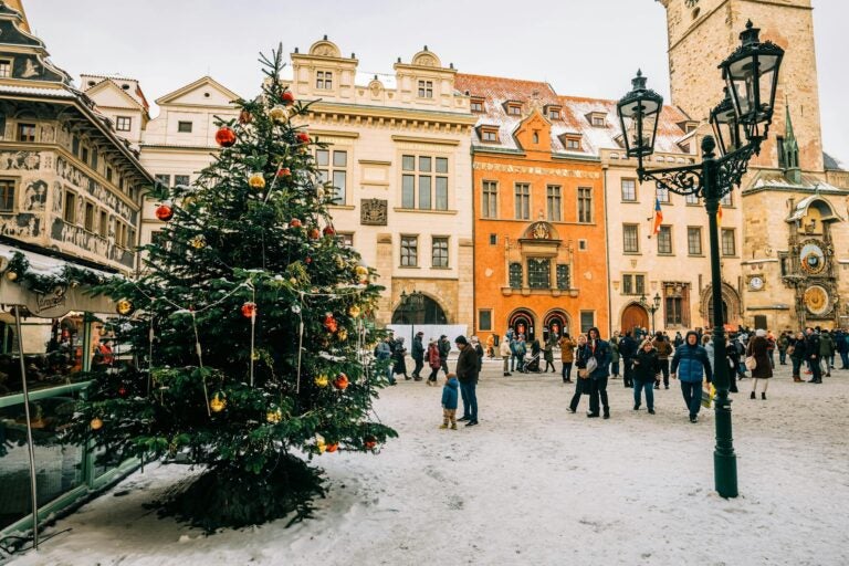 People walk around a square that hosts a Christmas tree in Prague Old Town.